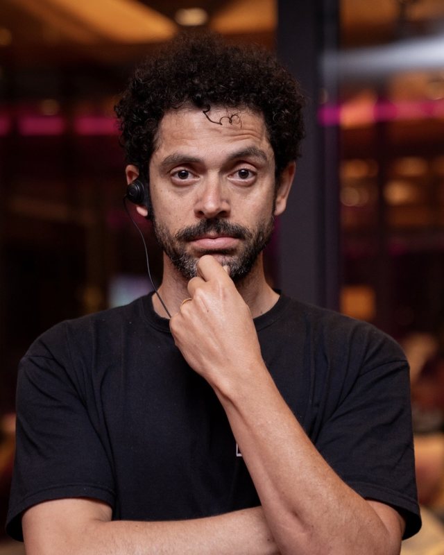 Retrato de Ivan Torres, com fone de comunicação e a mão no queixo