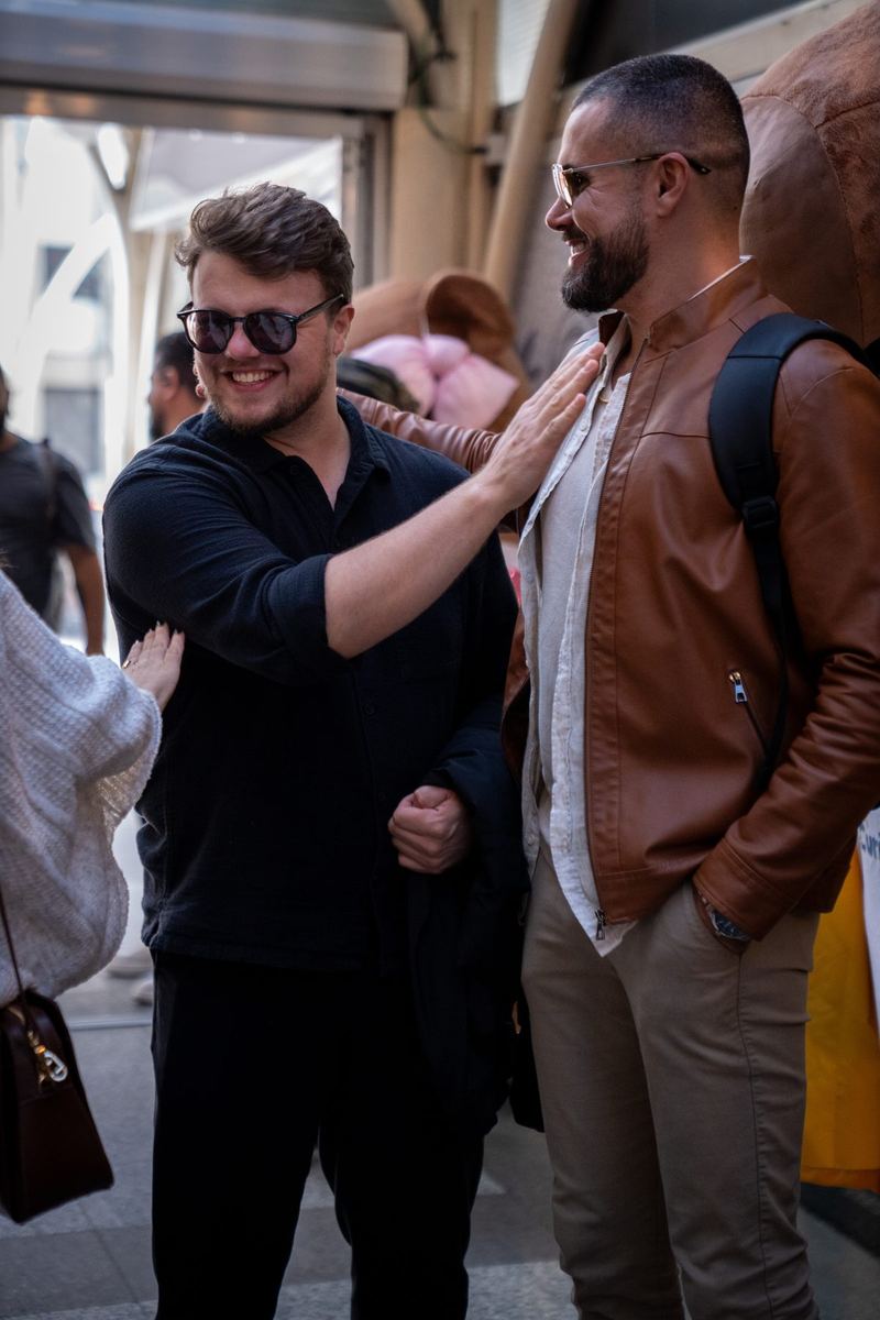 Dois homens conversando e rindo na entrada de uma galeria