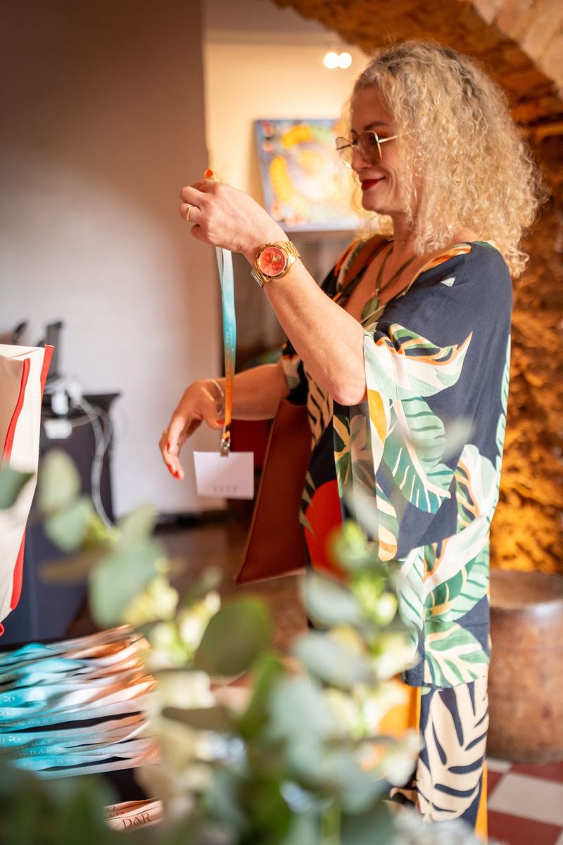 Mulher de cabelo cacheado entregando bolsa personalizada no credenciamento