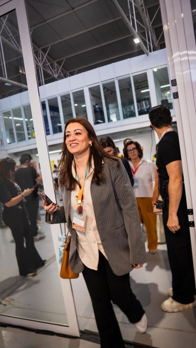 Participante com crachá sorrindo em evento realizado em galpão
